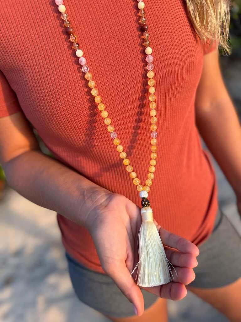 women holding yellow tassel with gold cone attached to citrine crystal necklace