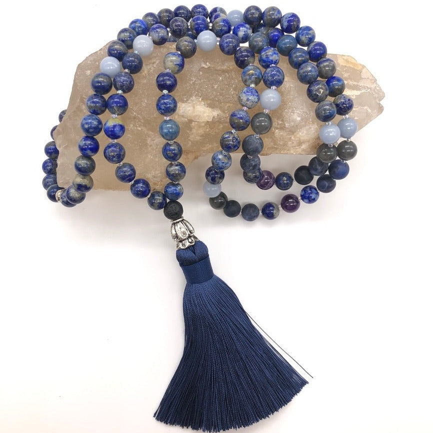 third eye necklace made with lapis lazuli gemstones with blue tassel sits on top of smokey quartz