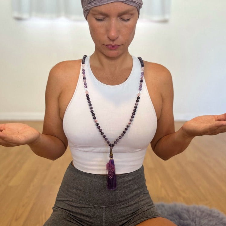 Women wearing amethyst crystal necklace while praying 