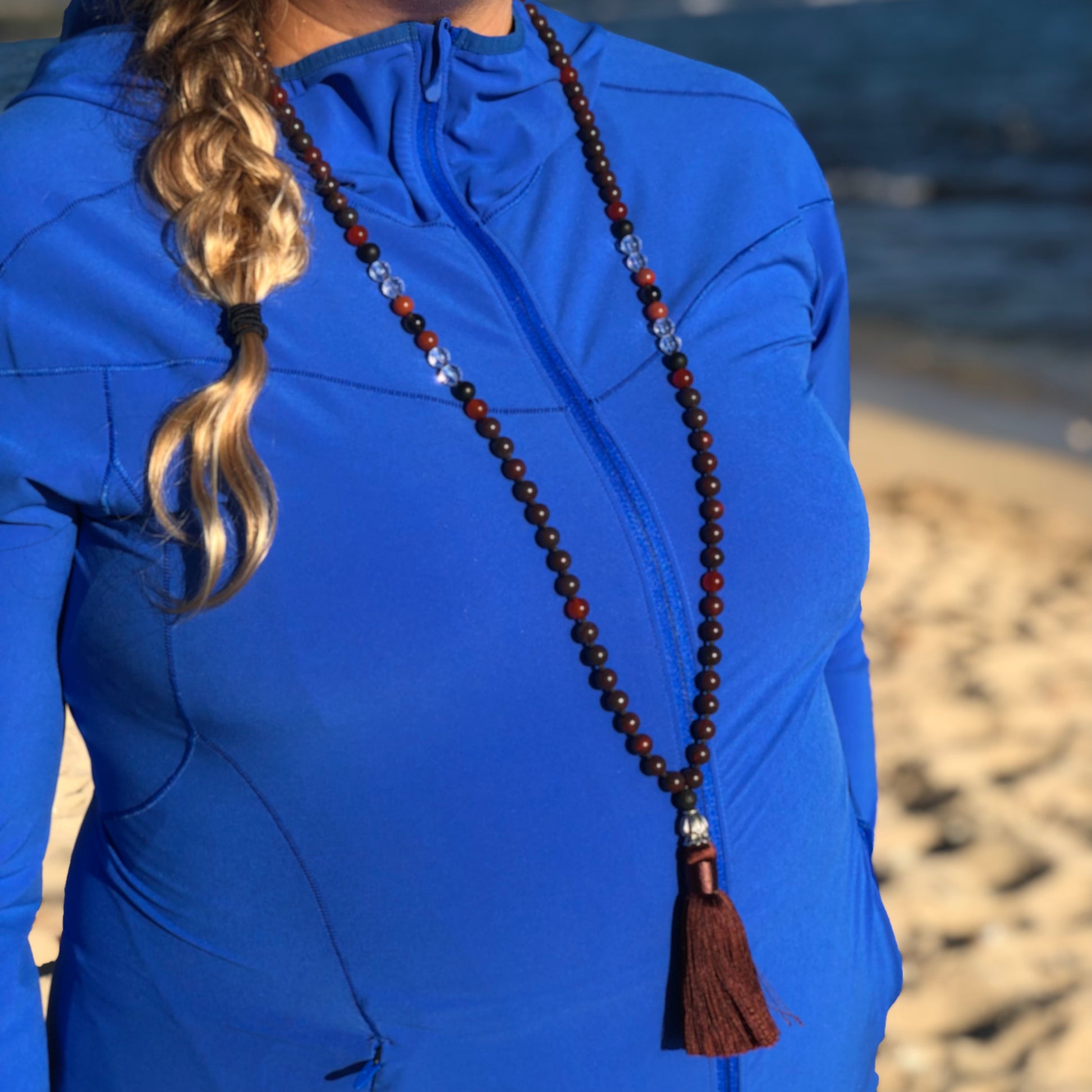 women at beach wearing red jasper necklace with tassel