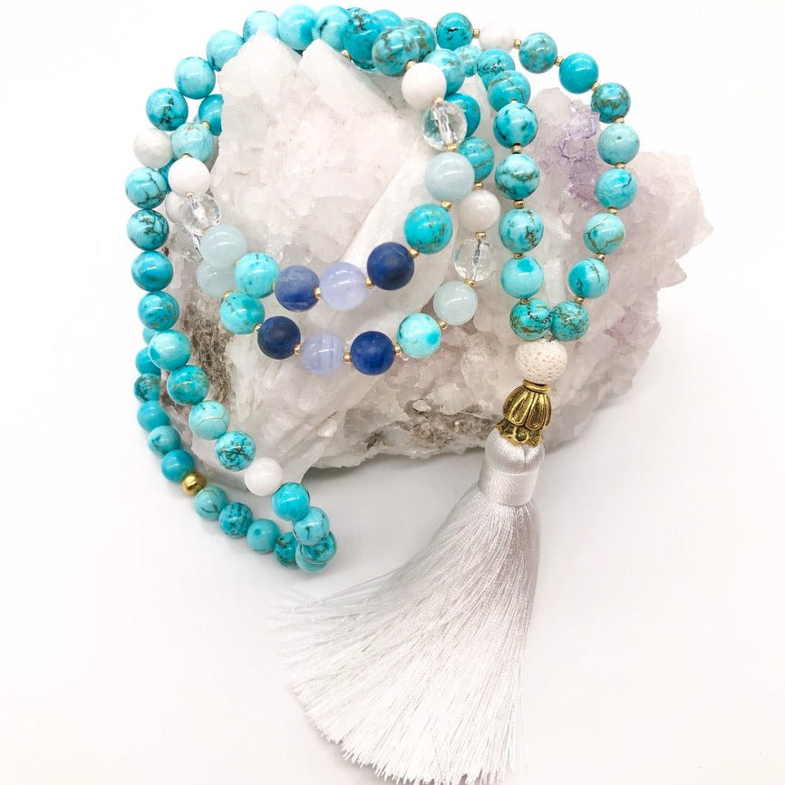 Turquoise stone necklace with white tassel sits on top of selenite crystal