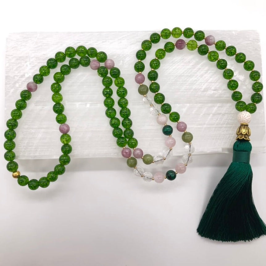 green crystal necklace made from peridot stones sits on top of selenite