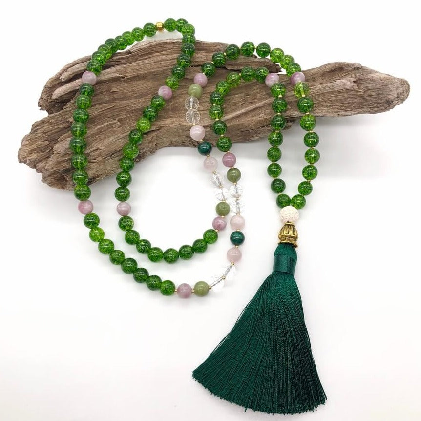 green crystal necklace with green tassle on top of wood