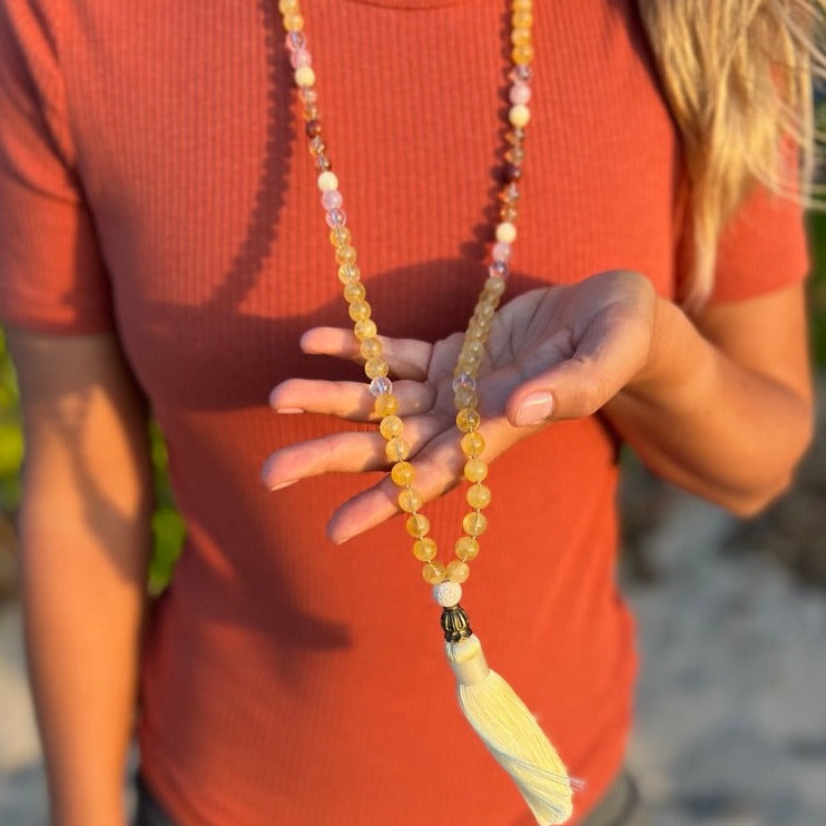 women wearing citrine crystal necklace on beach with yellow tassel 