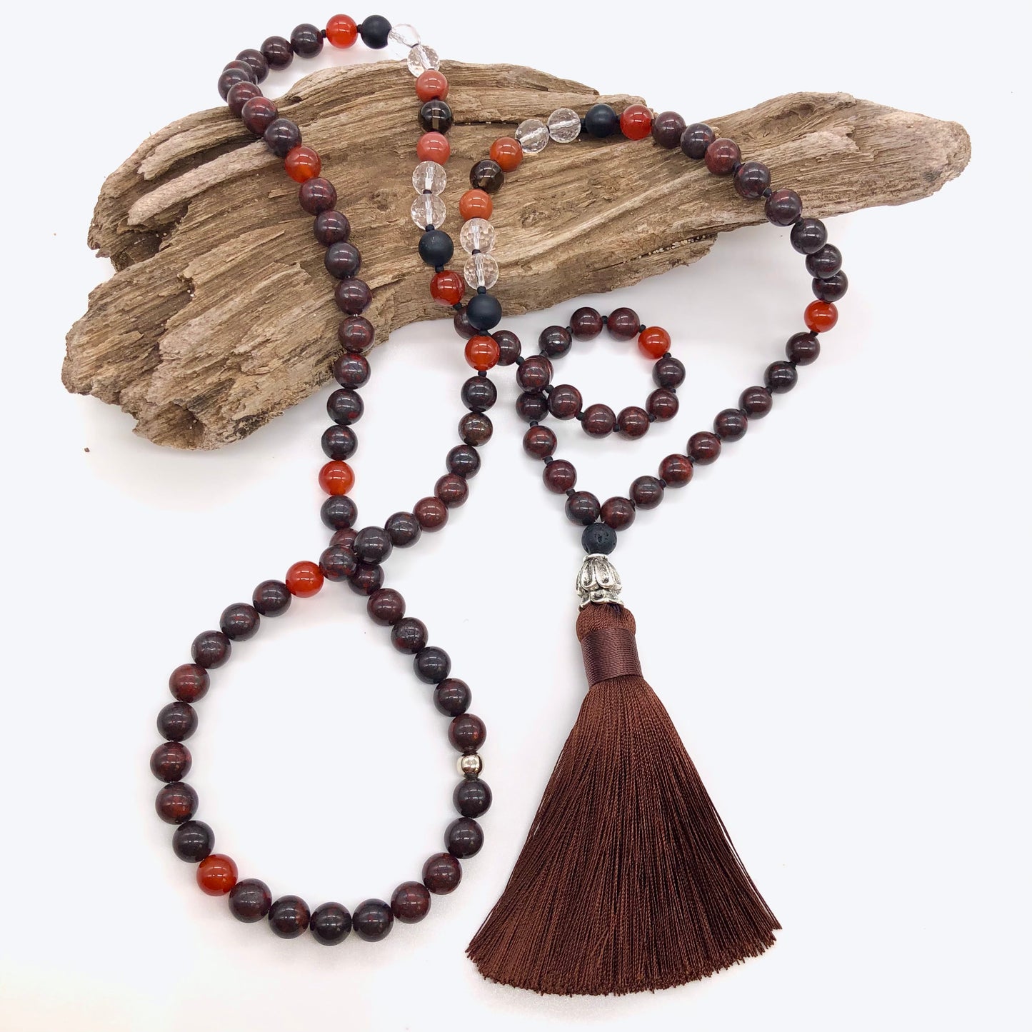 Red jasper necklace with tassel on top of wood