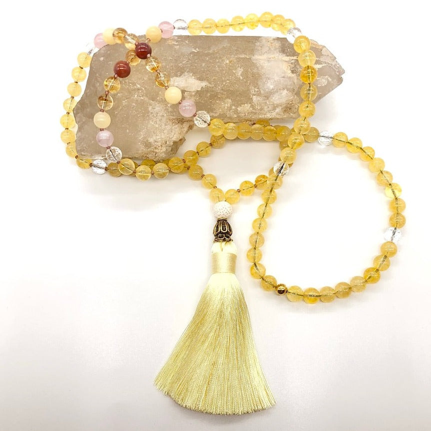 citrine crystal necklace with yellow tassel on top of smokey quartz