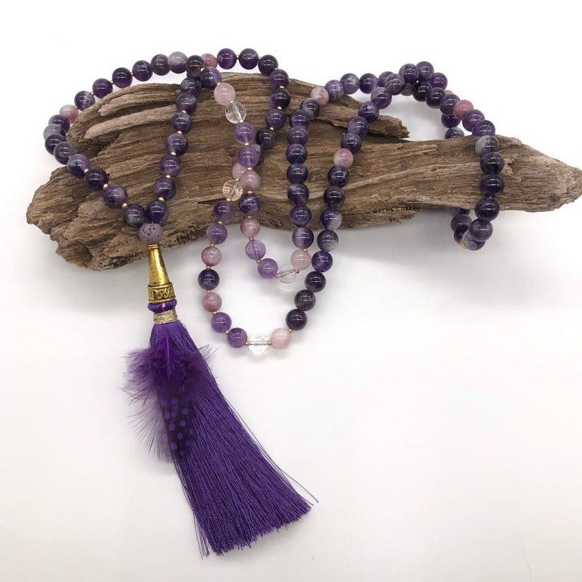 Amethyst crystal necklace with purple tassel on top of wood 