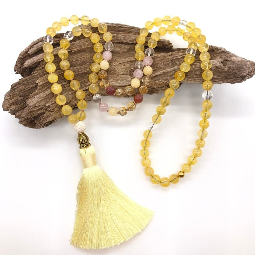 citrine crystal necklace with yellow tassel on top of wood